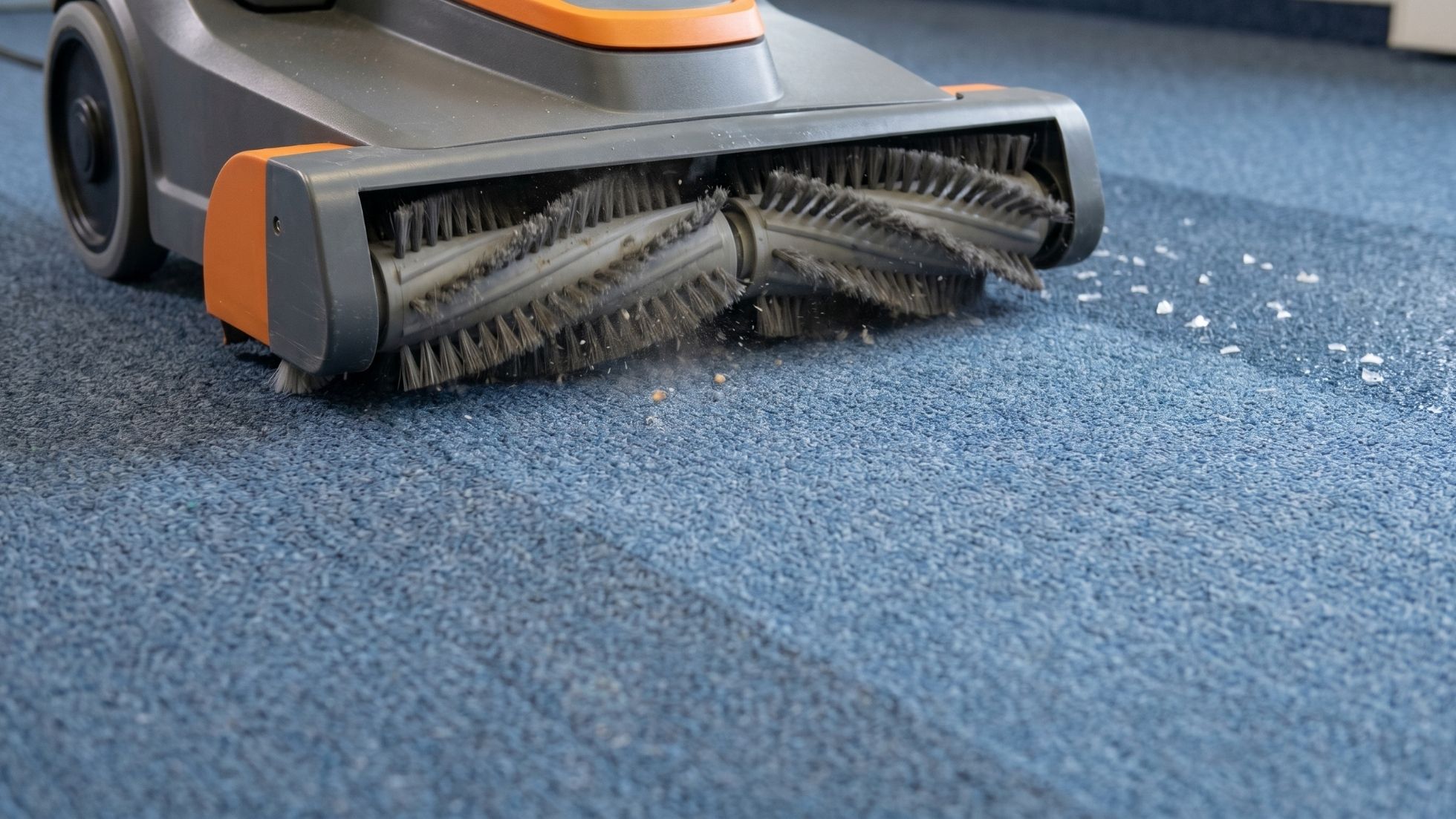 Commercial carpet cleaner with rotating brushes sweeping debris from blue office carpet for deep cleaning