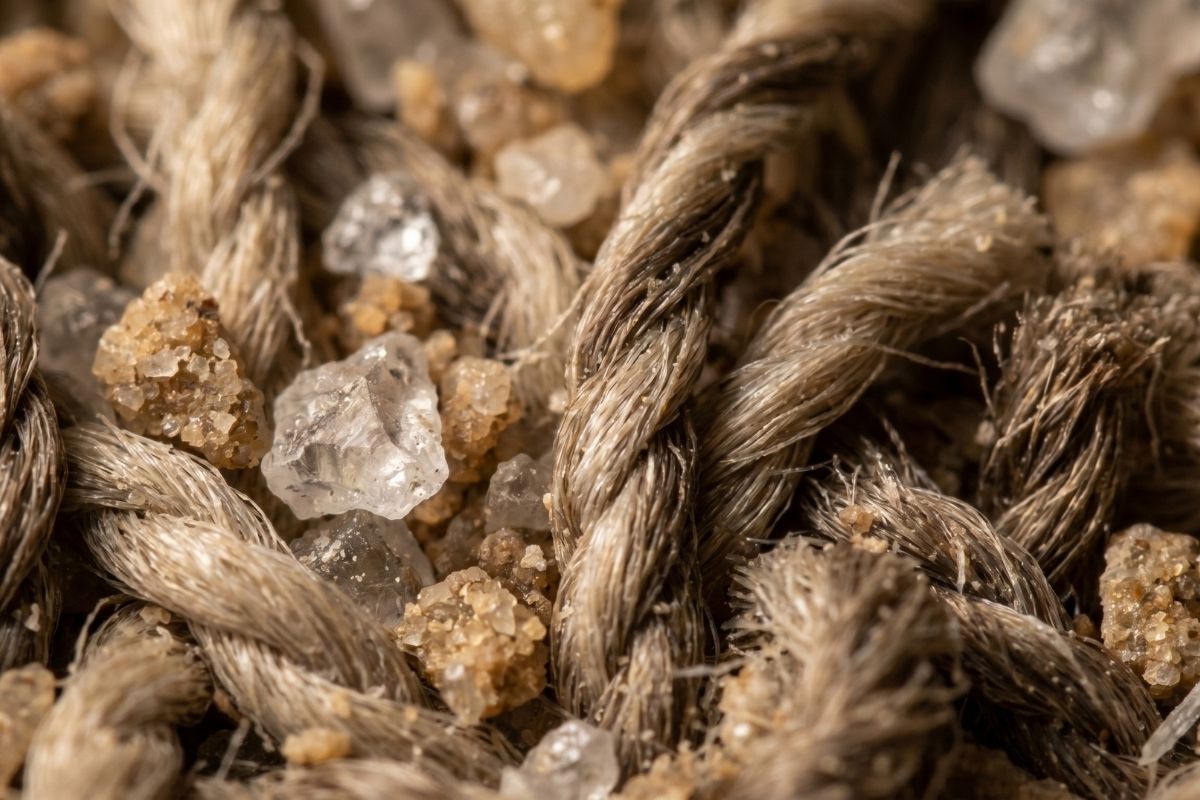 Macro close-up of natural fiber rope with coarse crystals and sand grains, rustic texture background